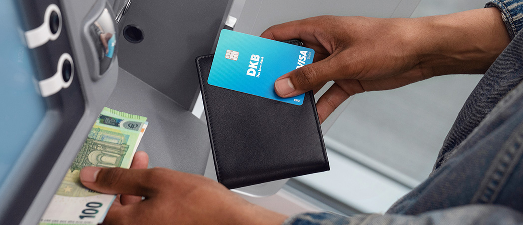 Person hebt mit Visa Debitkarte Bargeld am Geldautomaten ab