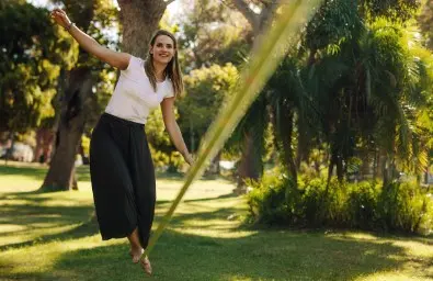 Eine Frau balanciert auf einer Slackline.