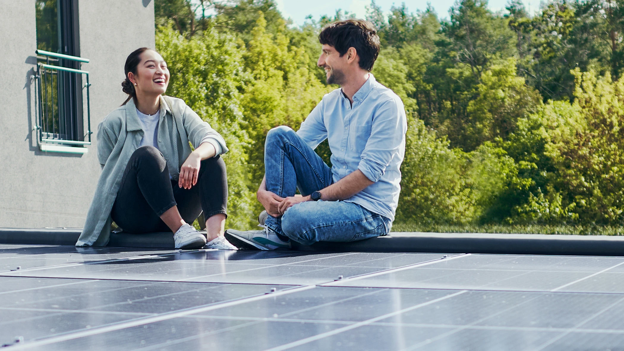 Eine Frau und ein Mann sitzen auf einem Flachdach mit Solarpanel.