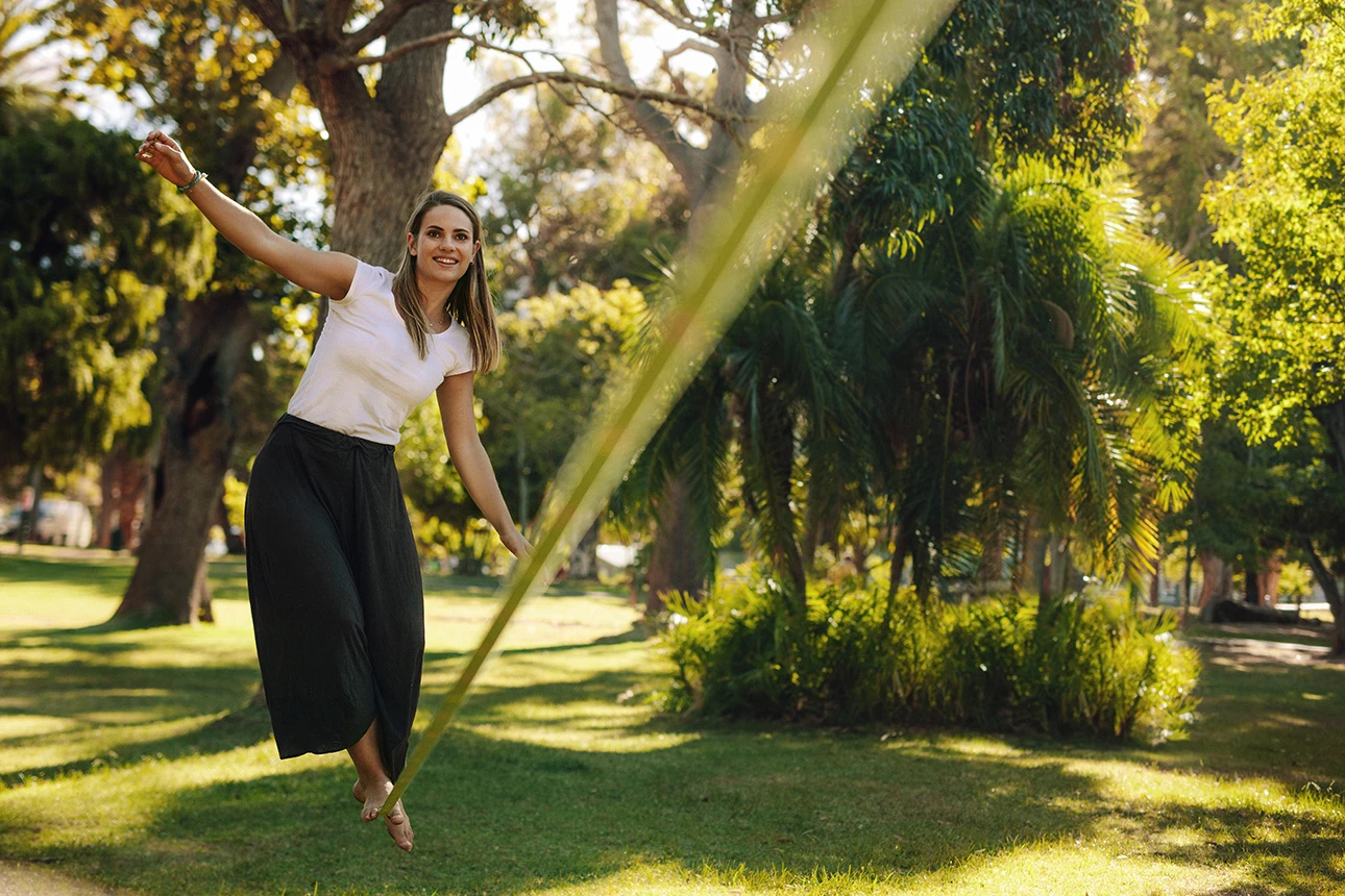 Eine Frau balanciert auf einer Slackline