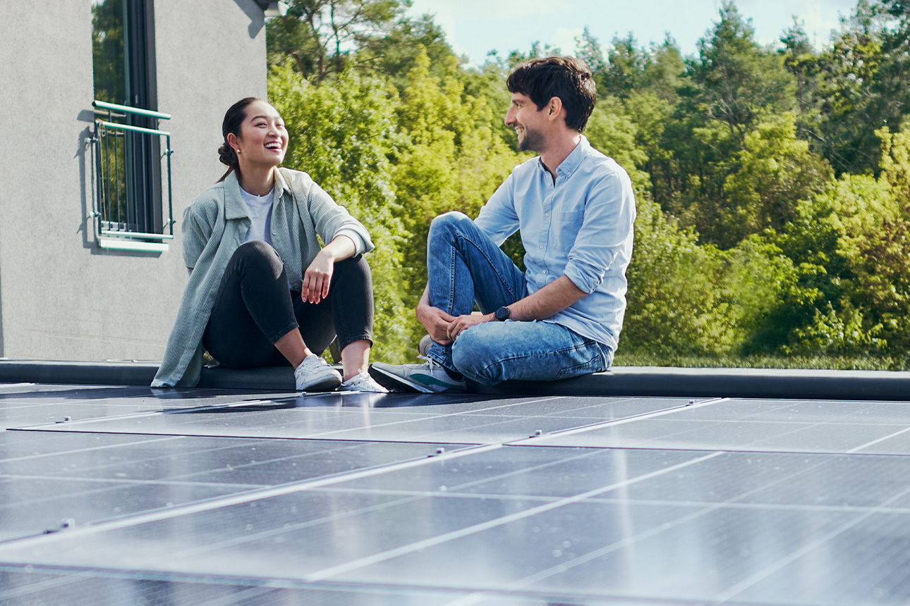 Paar freut sich über nachhaltige Solaranlage auf Garagendach.