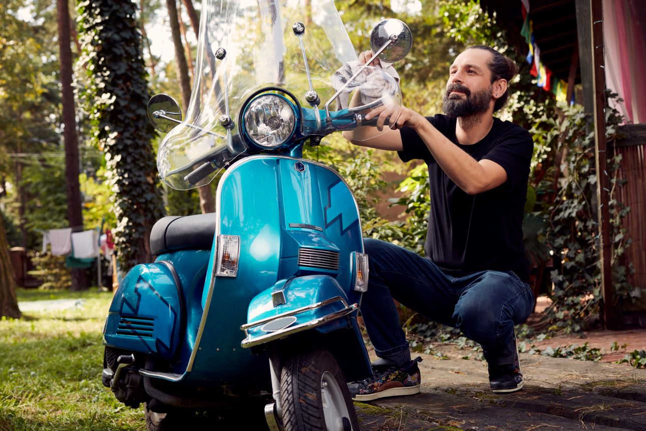Ein Mann putzt einen Motorroller.