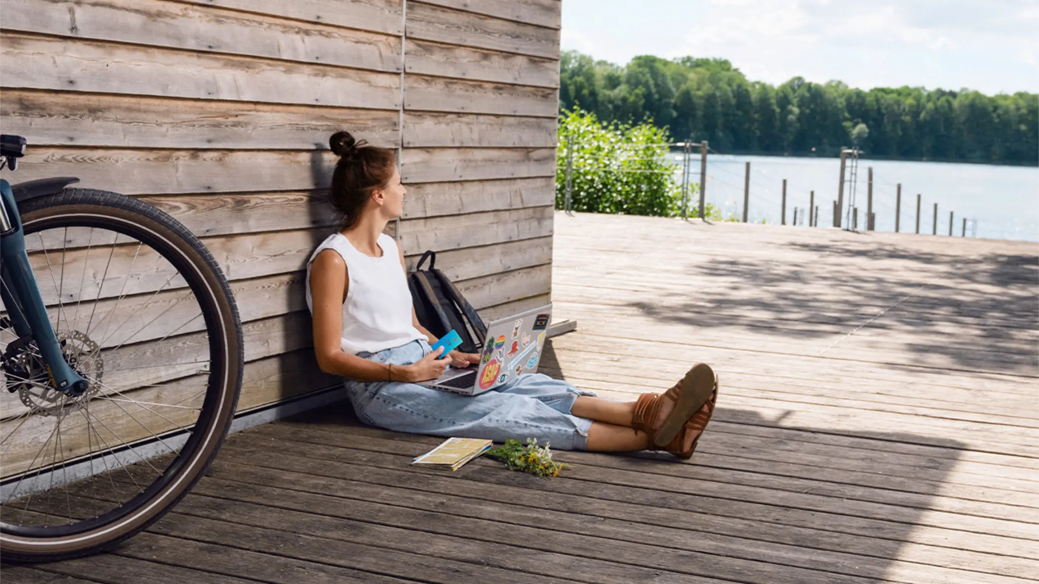 Eine Frau sitzt auf einem Steg und blickt auf einen See.