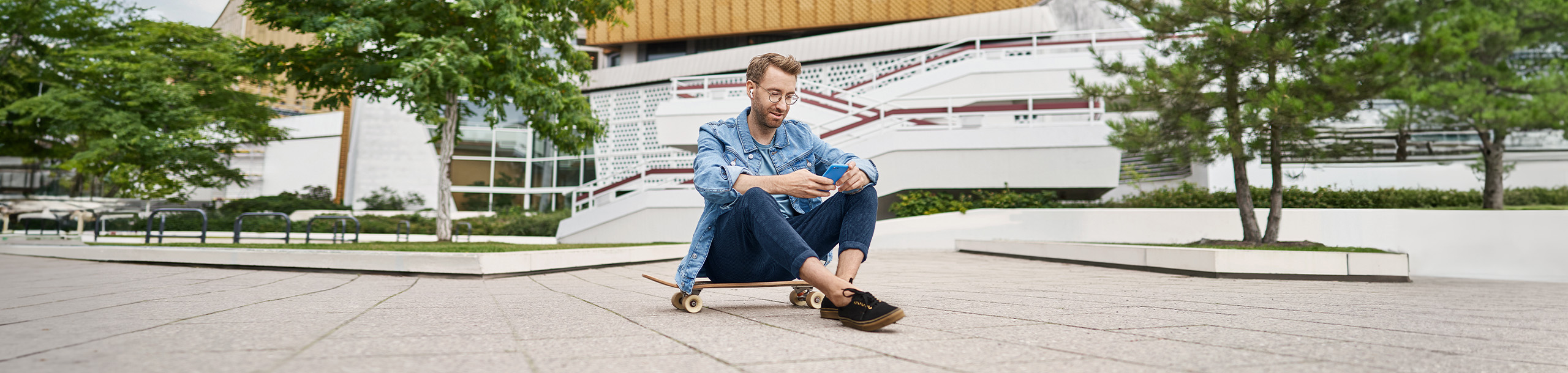 Mann mit Handy sitzt auf Skateboard