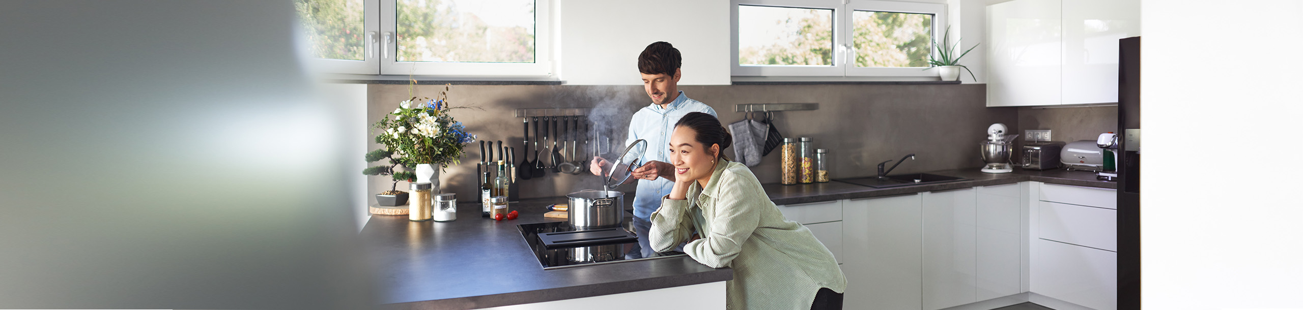 Junger Mann und junge Frau in moderner Küche beim Kochen.