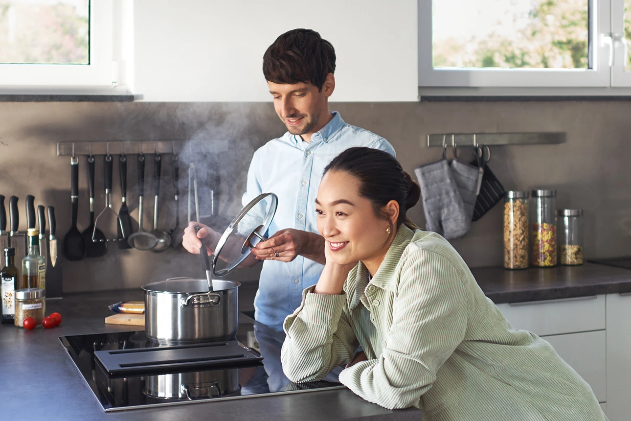 Junger Mann und junge Frau in moderner Küche beim Kochen