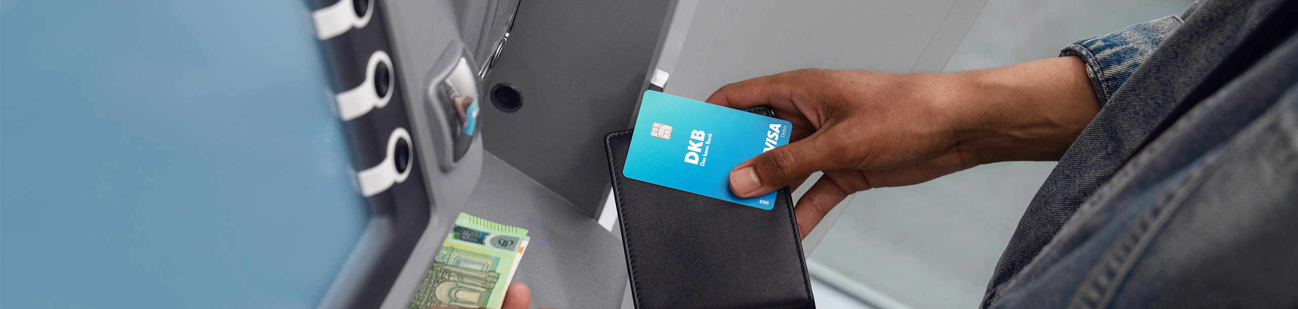 Person hebt mit Visa Debitkarte Bargeld am Geldautomaten ab