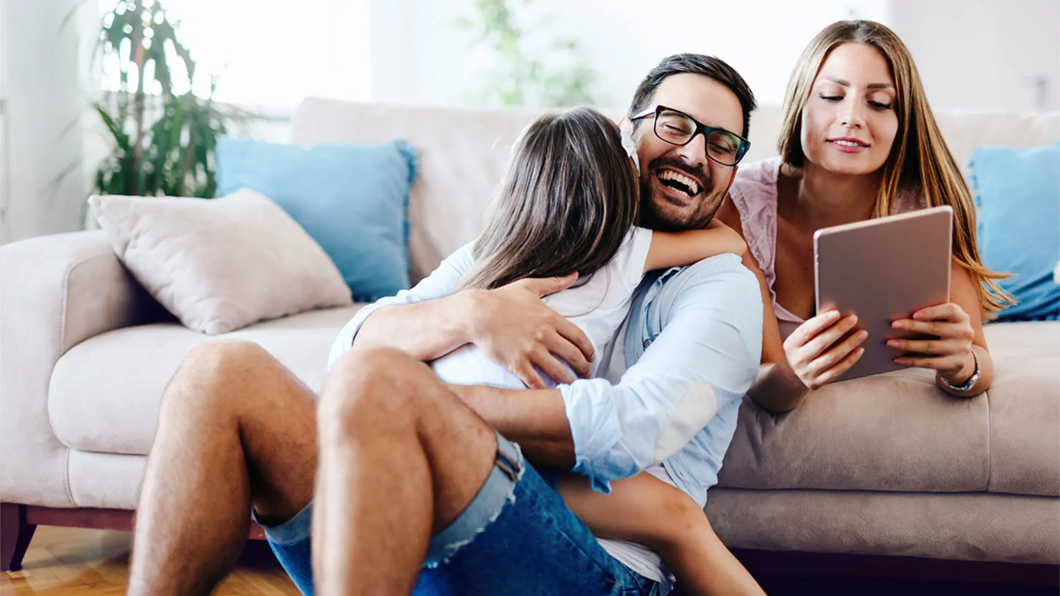 Ein Frau und ein Mann spielen mit einem Kind auf der Couch.