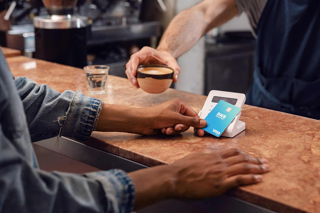 Person bezahlt mit Debitkarte am Kartenterminal im Café