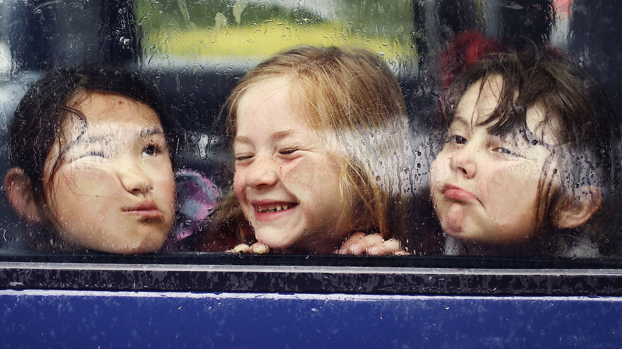 Kinder drücken ihre Gesichter von innen gegen Autoscheibe