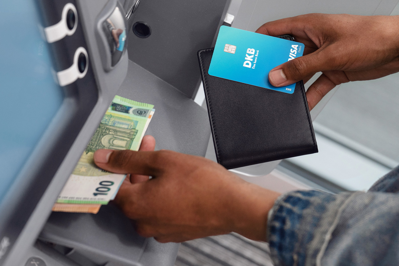 Ein Mensch holt mit seiner DKB Debitkarte Bargeld aus einem Automaten ab