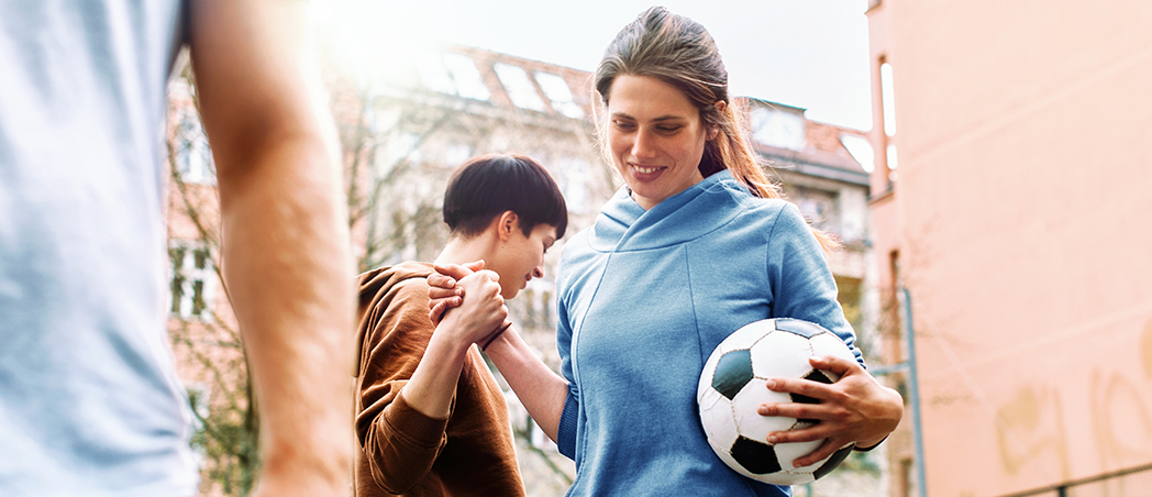 Frau mit Fußball klatscht andere Frau ab