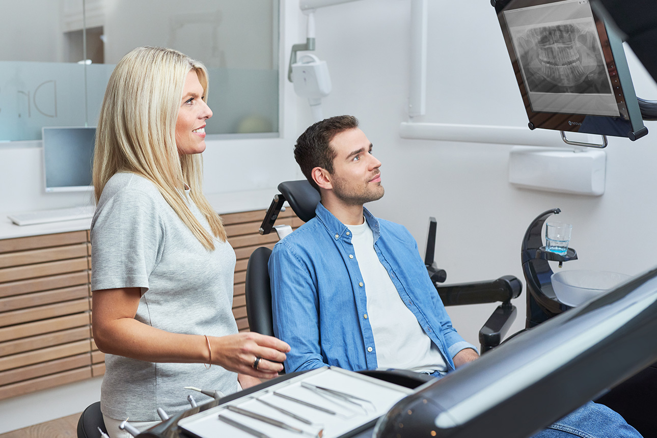 Zahnärztin und Patient schauen auf Monitor