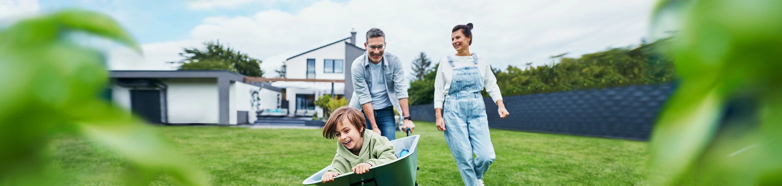 Familie spielt fröhlich im Garten des eigenen Hauses