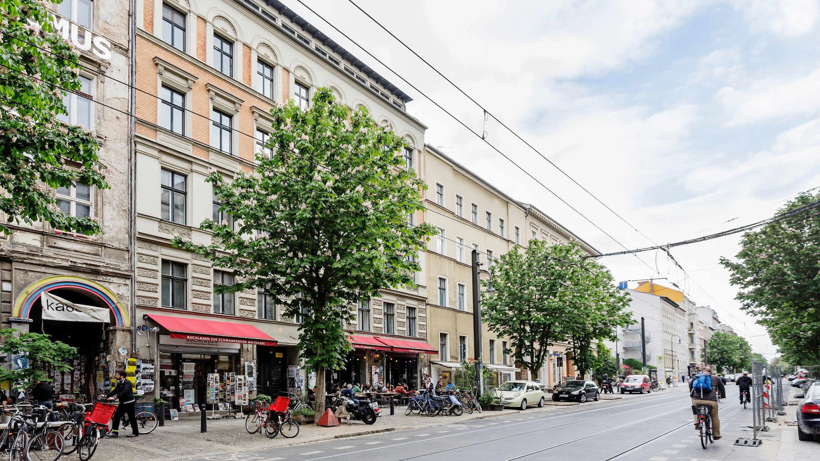 Schräger Blick auf die Fassade eines Altbau-Mehrfamilienhauses mit Geschäften im Erdgeschoss in der Kastanienallee in Berlin.