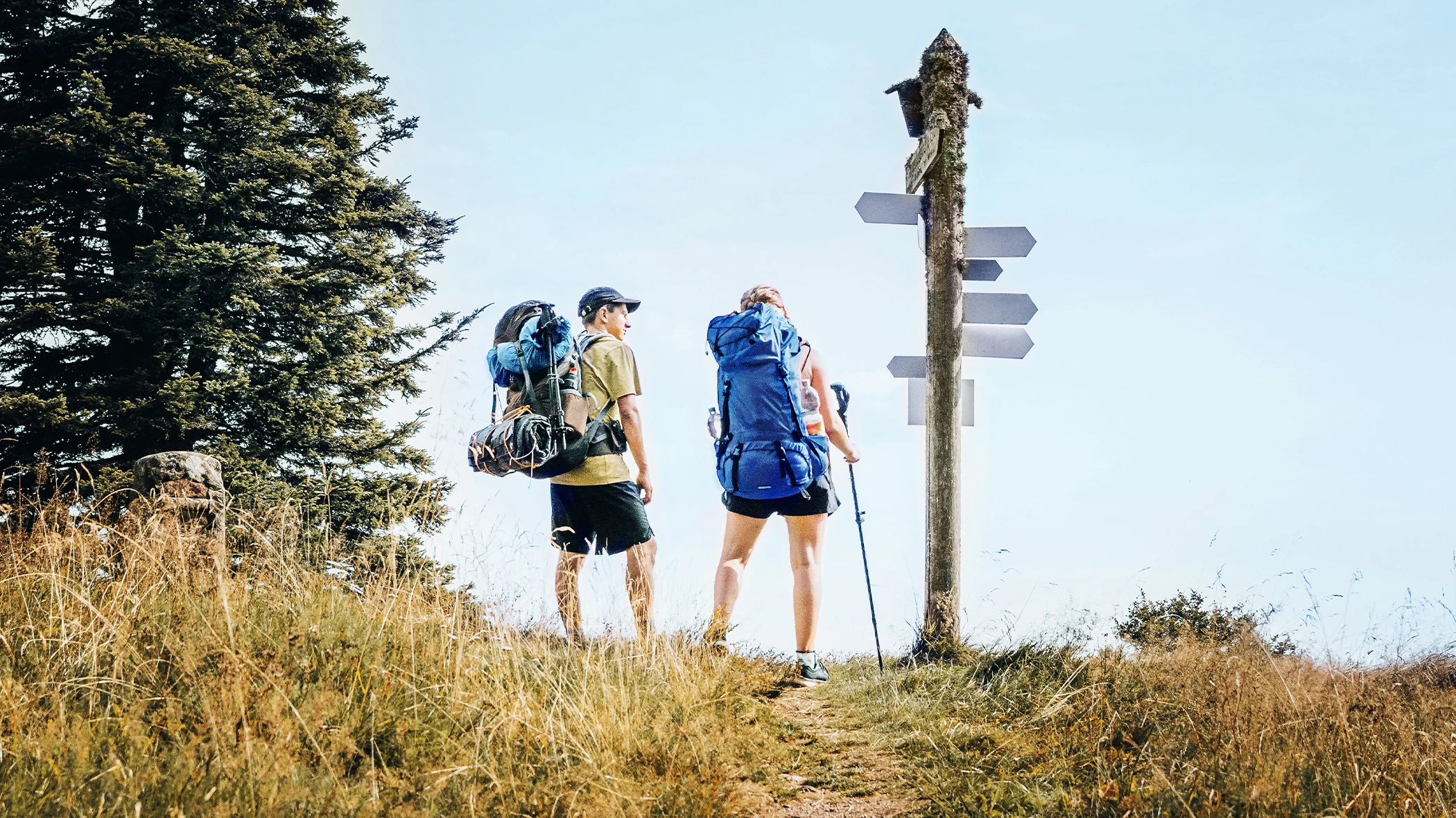 Ein Pärchen beim Wandern steht vor einem Wegweiser.