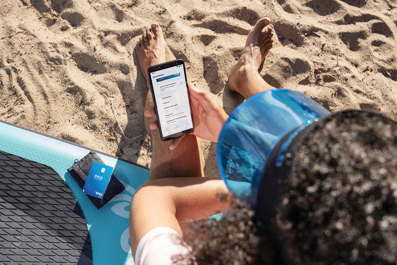 Eine Person am Strand hält ein Smartphone in der Hand