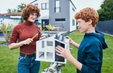 Eine Frau und ein Junge werkeln im Garten eines Hauses.