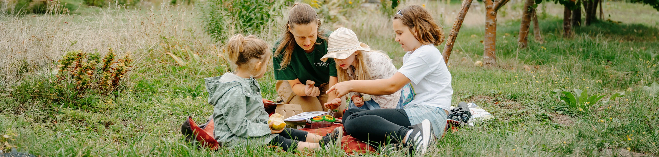 Kinder sitzen auf Wiese