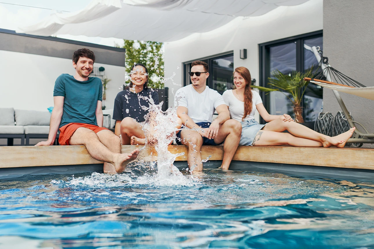 Zwei Männer und zwei Frauen sitzen an einem Pool