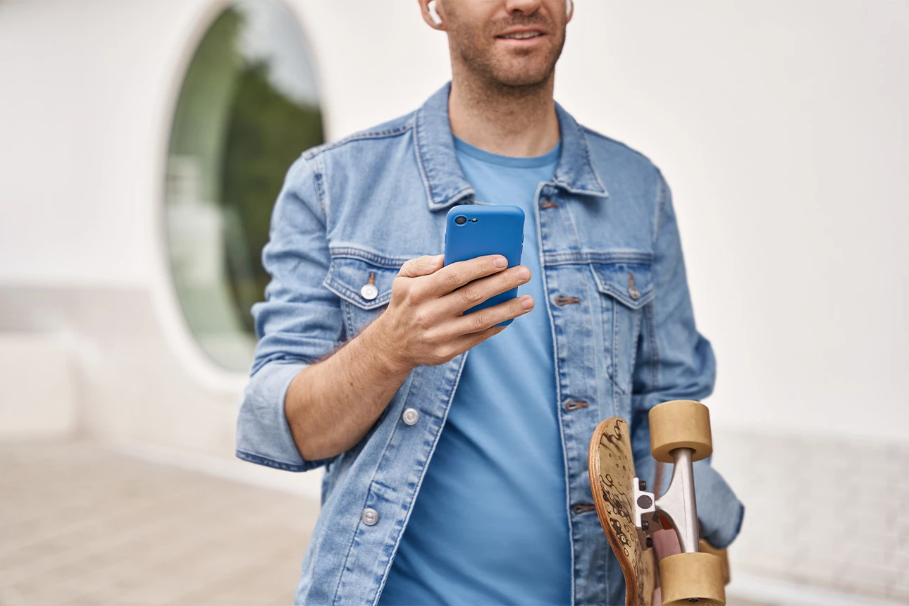 Mann mit Handy und Skatboard in der Hand