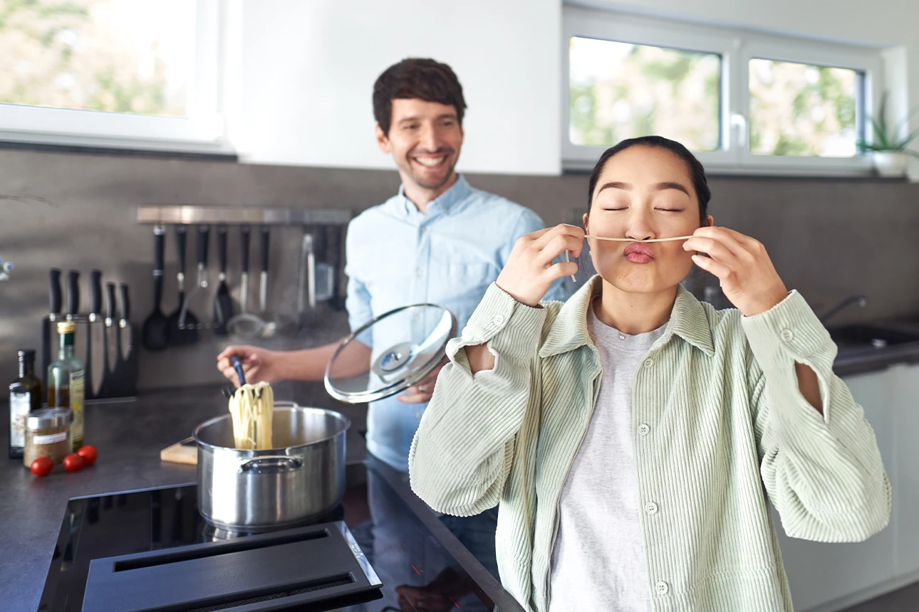 Junger Mann und junge Frau in moderner Küche beim Kochen.