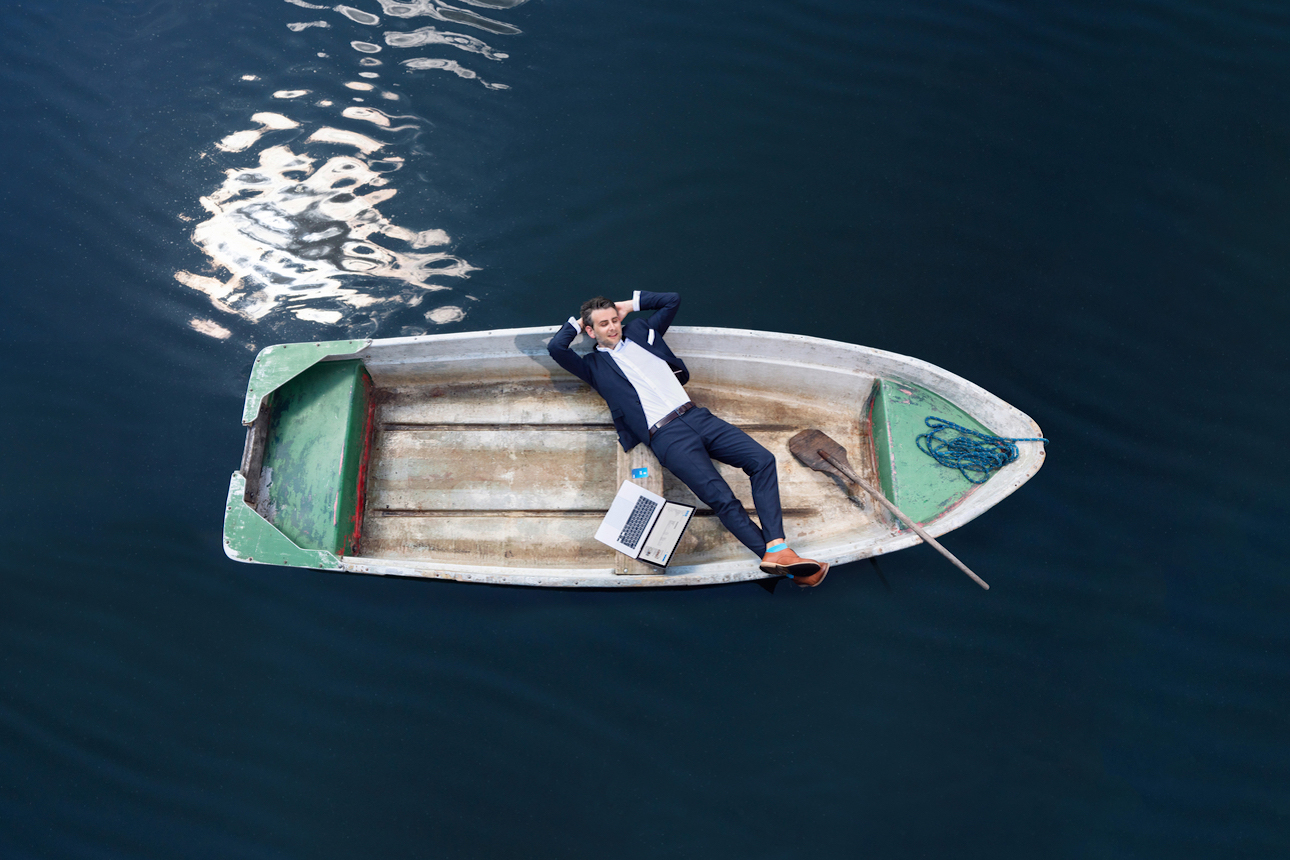 Ein Mann liegt auf einem Boot mit Laptop und einer DKB Visa Kreditkarte