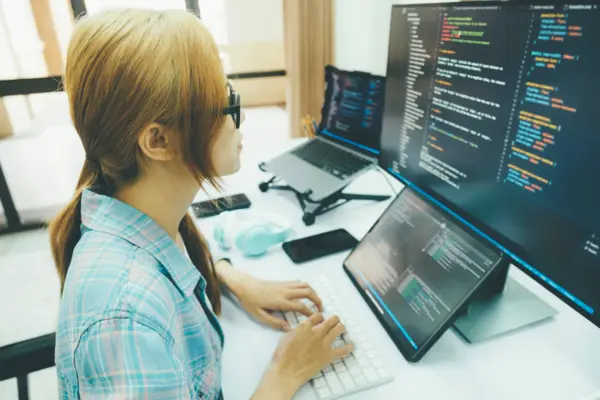 female coder on multiple screens