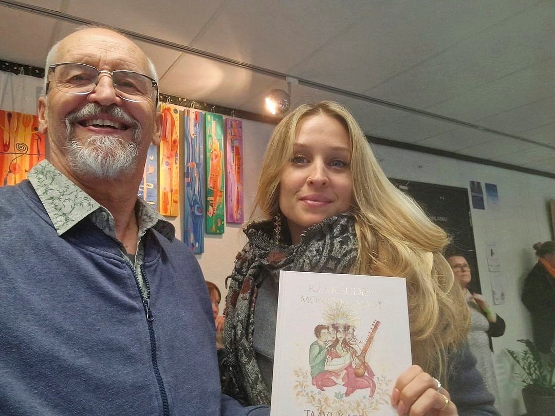 Taavi Kassila ja Oona-tytär. Oona pitelee kädessään Rakkauden monet kasvot -kirjaa, jonka kansikuvan hän on maalannut.