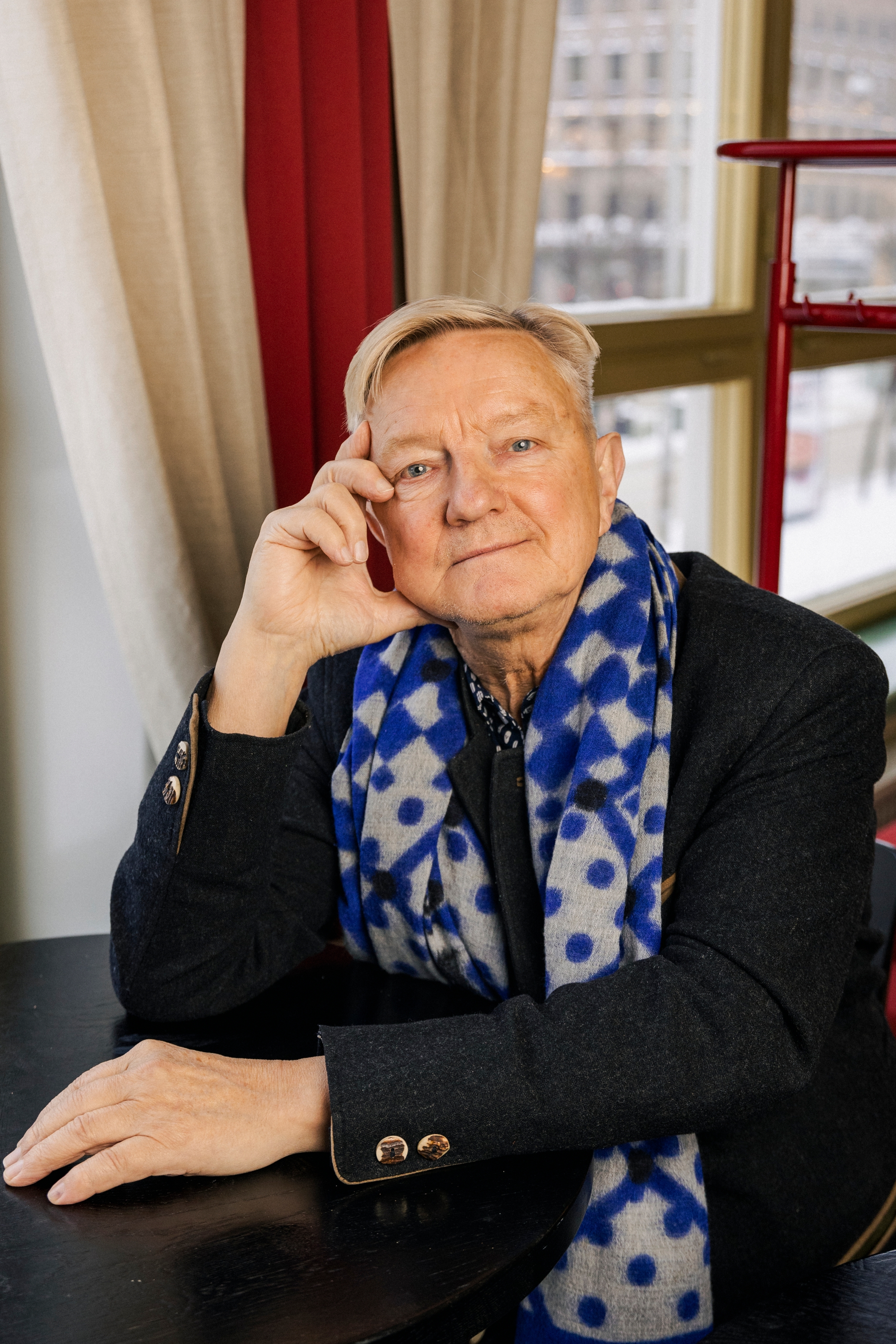 Hannu Väisänen katsoo kameraan, istuu pöydän ääressä.