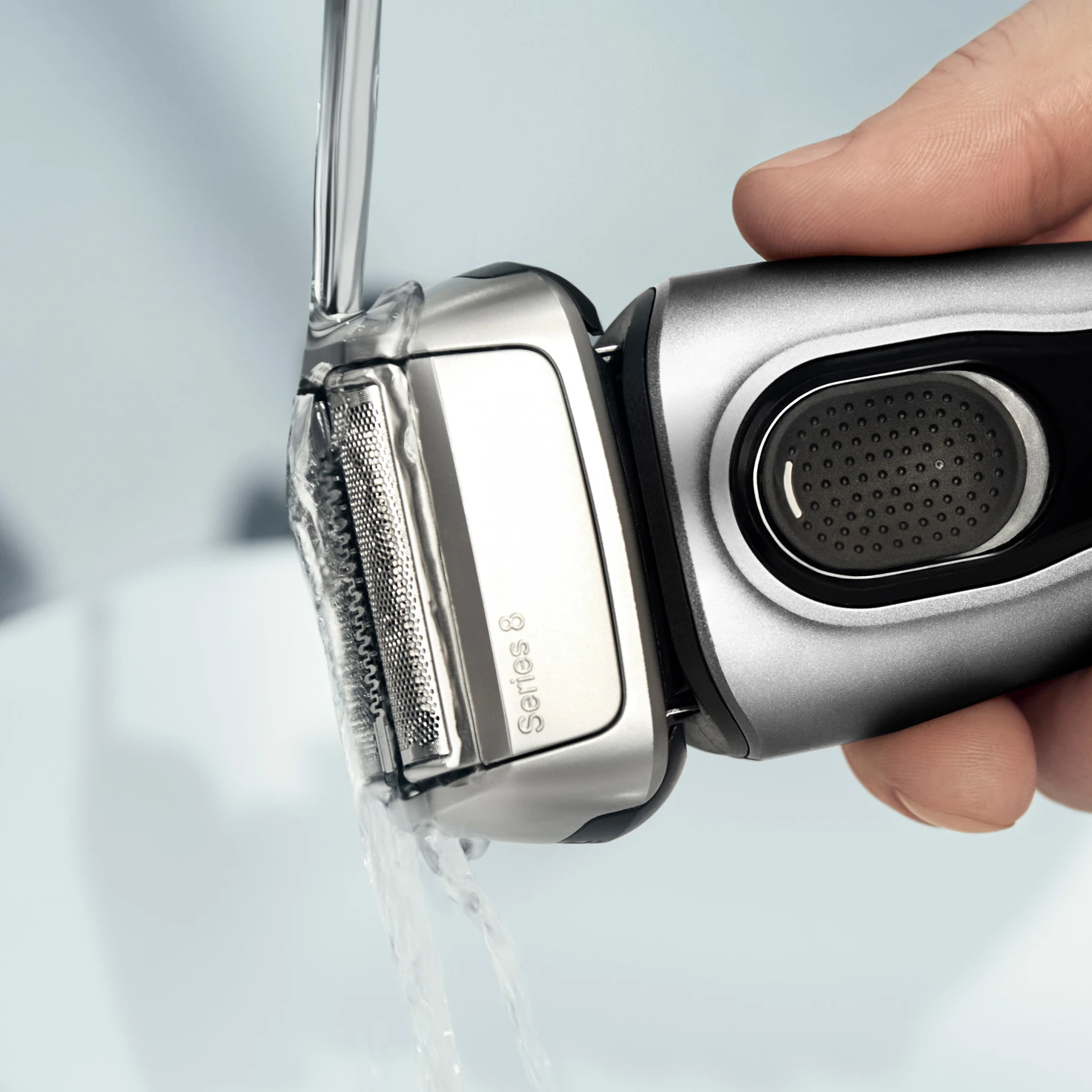 Hand rinses shaver under running water