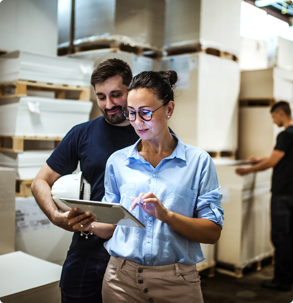 Two warehouse workers reviewing inventory on a tablet.