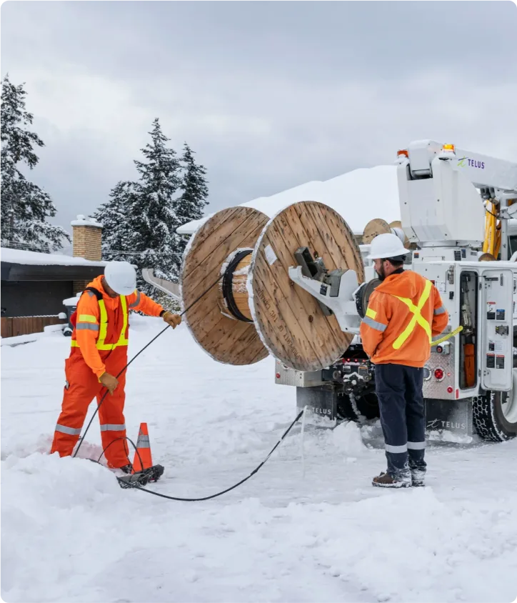 Deux techniciens de TELUS installant une ligne filaire souterraine