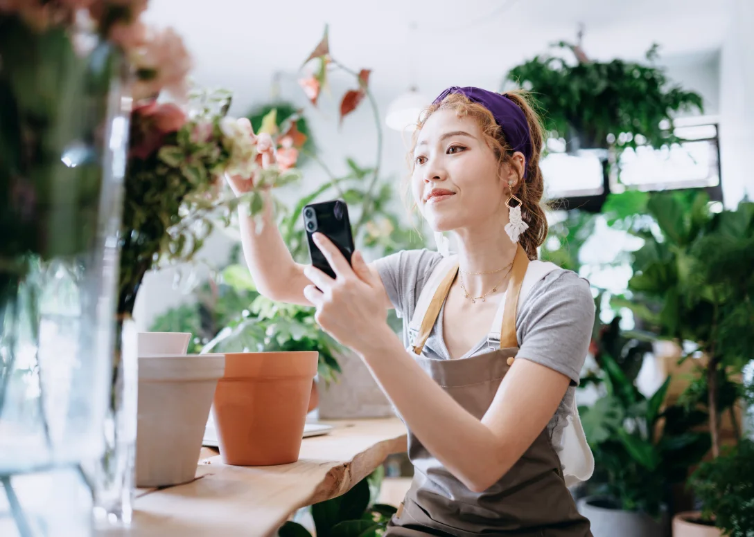 Person using their mobile device while working in a flower shop.