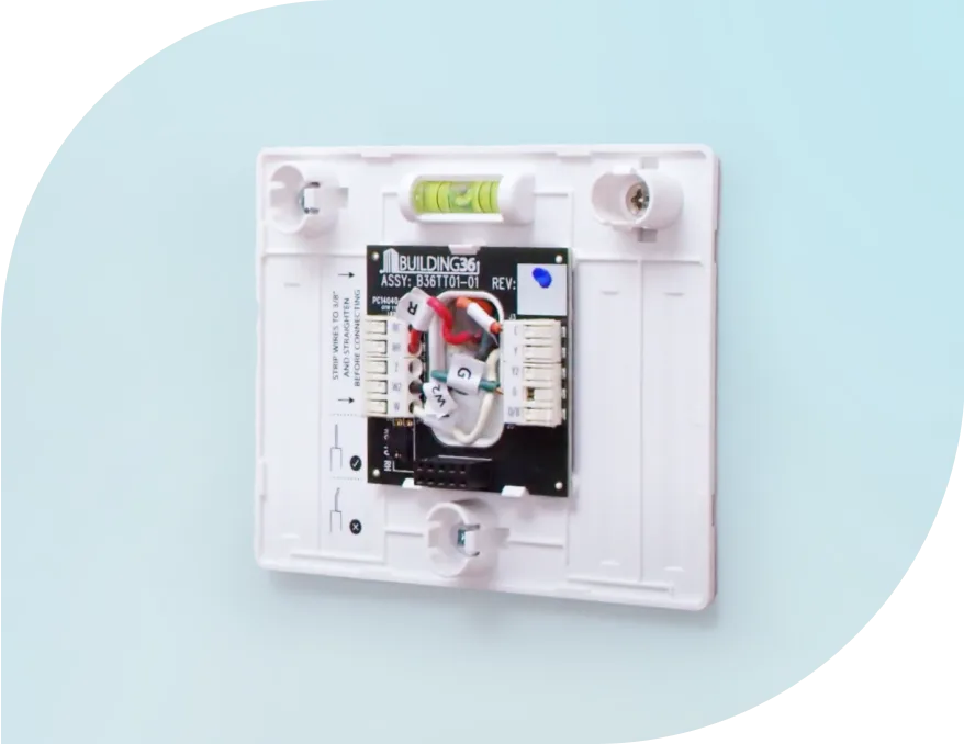 Un thermostat intelligent partiellement installé sur un mur, illustrant les rouages internes du dispositif.