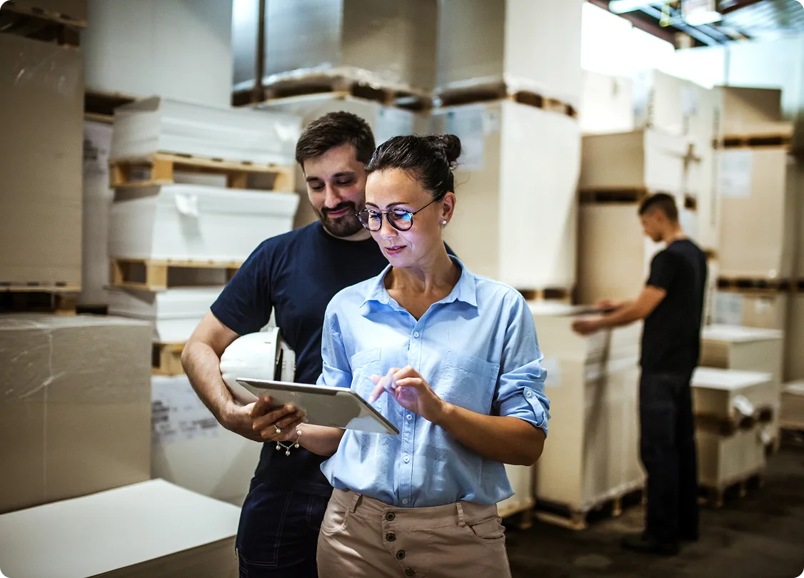 Warehouse staff using tablet for inventory management.