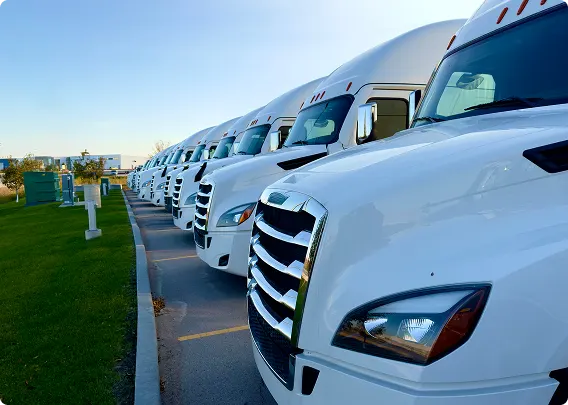 Row of white semi-trucks parked in commercial TELUS Raven-powered fleet lot.