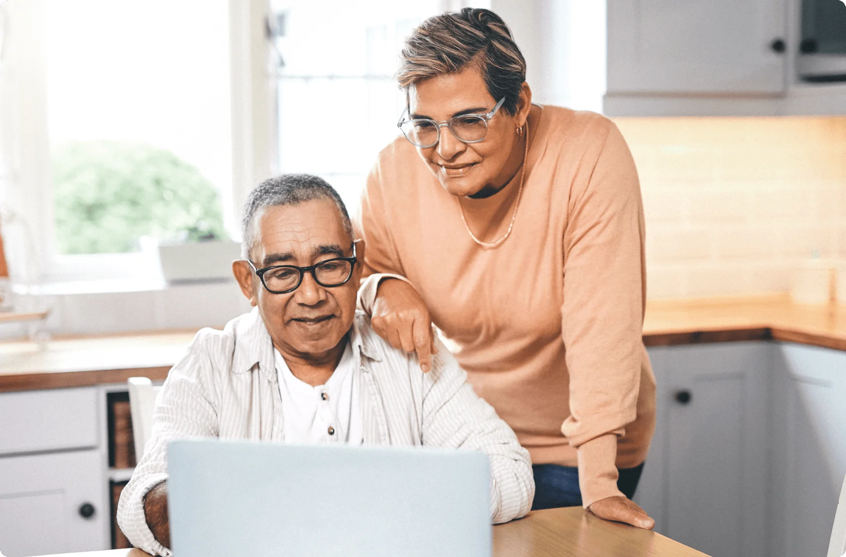 Un couple âgé est à l’ordinateur. La personne à gauche est assise et celle à droite s’appuie sur l’épaule de l’autre.
