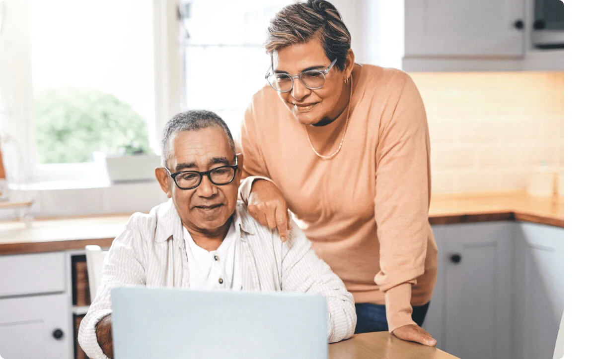 An older couple enjoy interacting with their laptop.