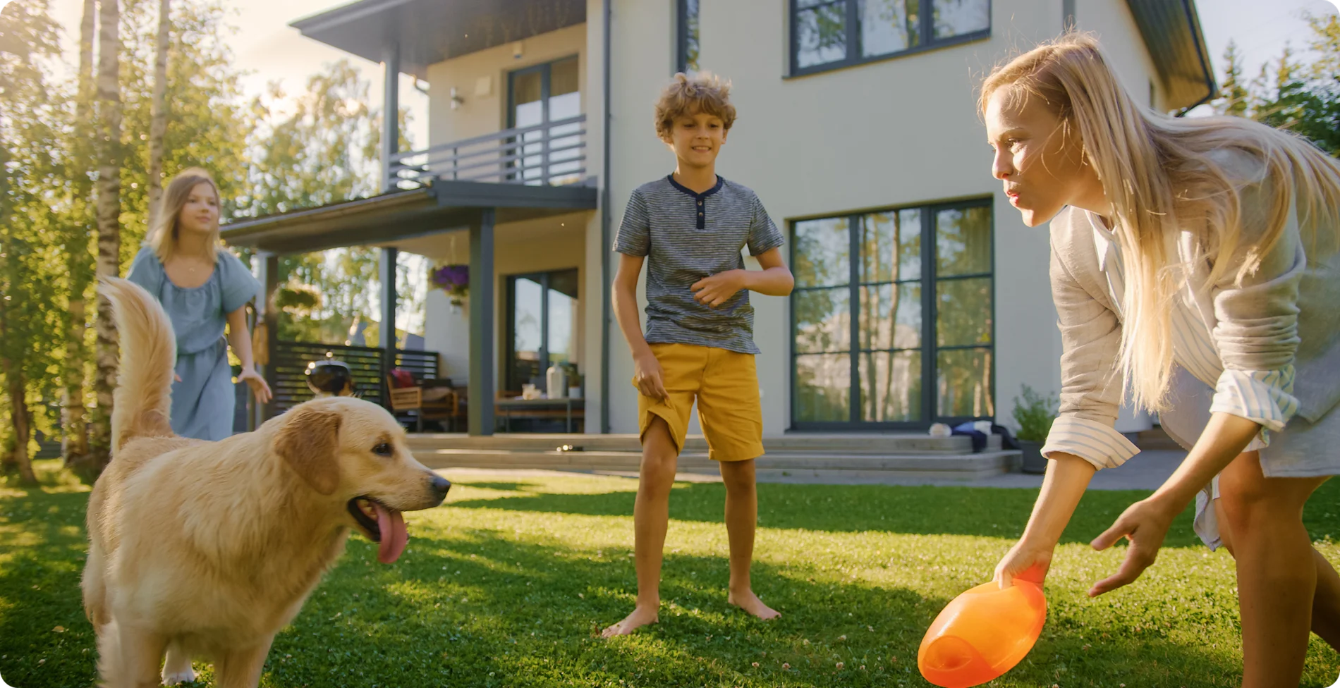 Famille avec chien jouant dans la cour avant d’une maison moderne à deux étages