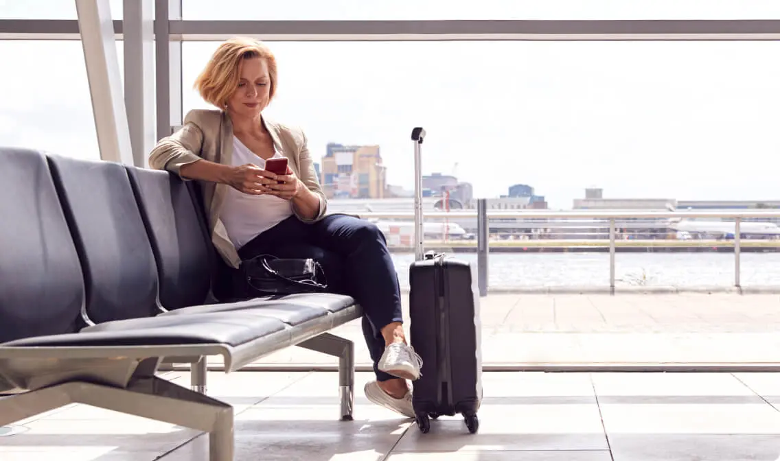 Woman engaging with her phone while relaxing in an airport lounge.