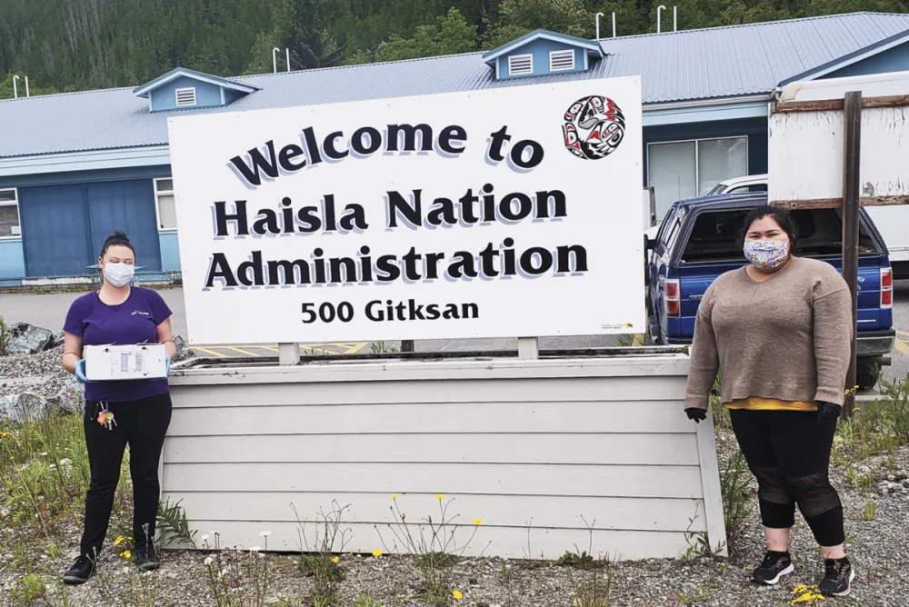 Un membre de l’équipe TELUS et un membre de la communauté autochtone Haisla à côté d’une enseigne Bienvenue.
