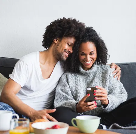 Couple assis sur un canapé et regardant les vidéos captées par les caméras sur l’application TELUS MC+.