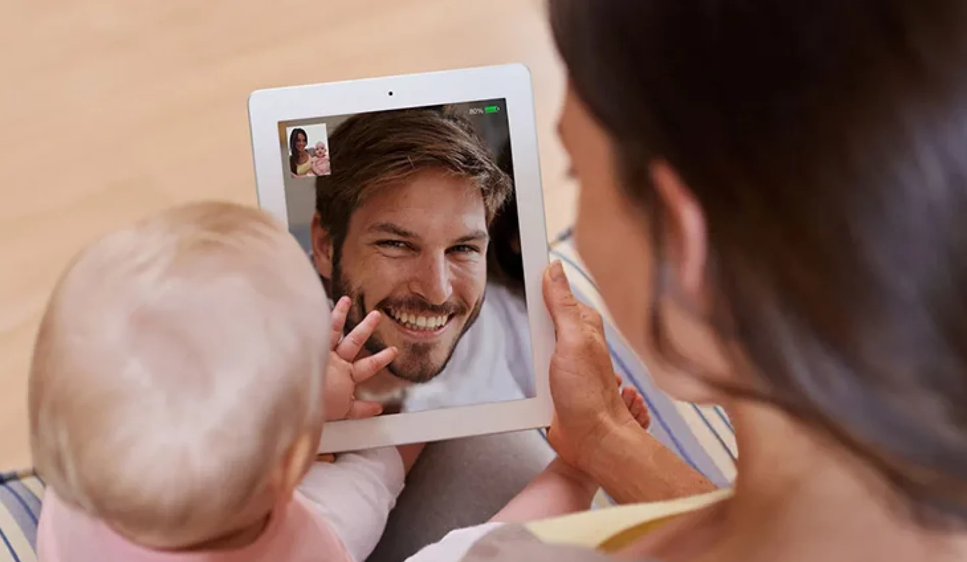 An image showing a mother and her child communicating with her husband via tablet.