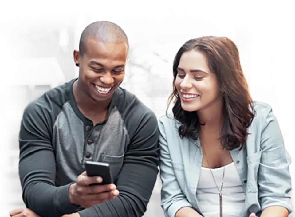 A man and a woman smiling while looking at a 5G device
