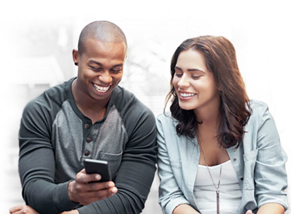 Un homme et une femme qui sourient en train de regarder un téléphone mobile 5G