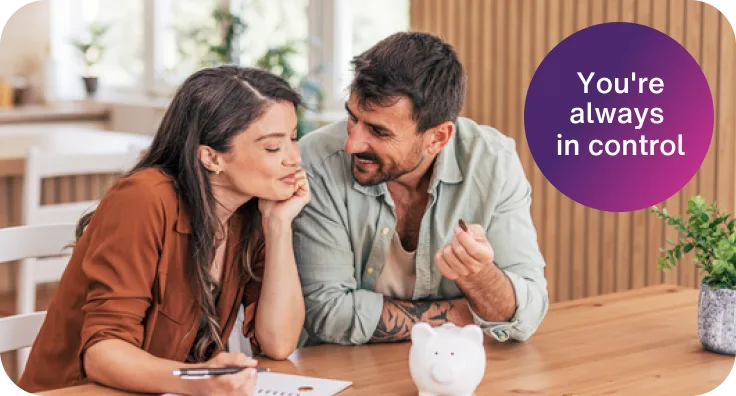A couple sits at a table with a piggy bank and a notepad, discussing finances. A purple circle reads, "You're always in control."
