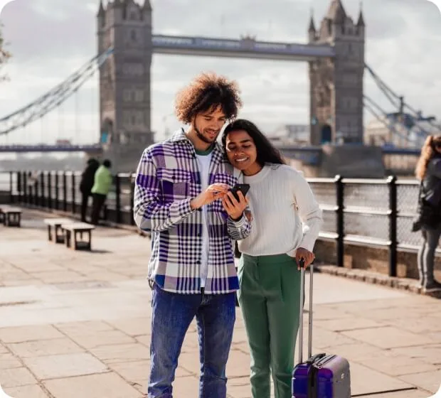 Couple using smartphone while traveling with luggage