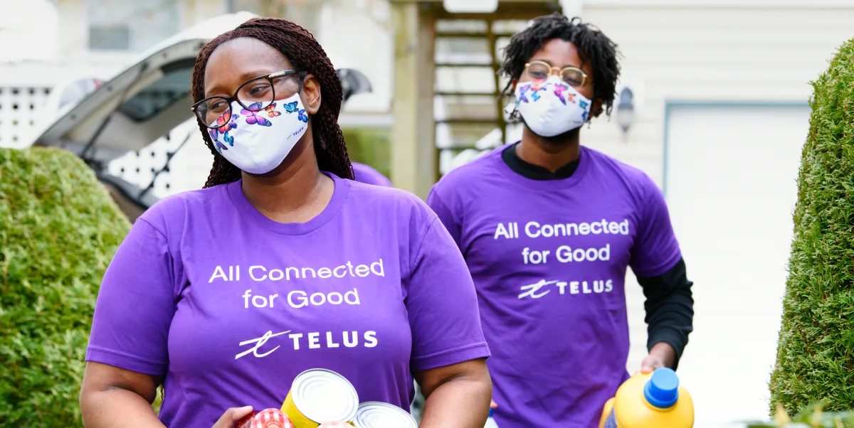 Deux bénévoles de l’équipe TELUS portant un t-shirt Tous connectés pour un monde meilleur.