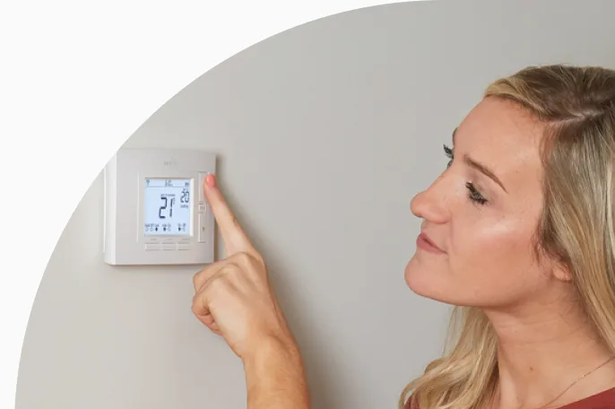 Woman setting a smart thermostat 